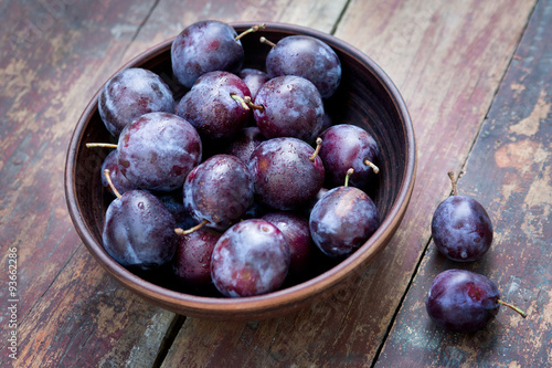 Plums in a bowl on the wooden table