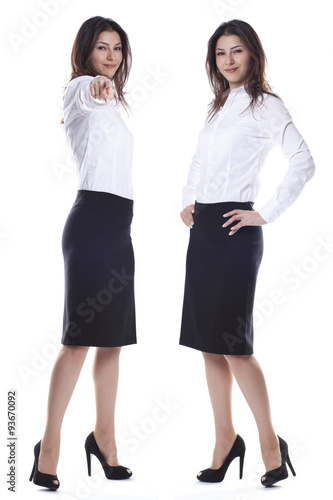 Twin business women are standing, smiling and showing us