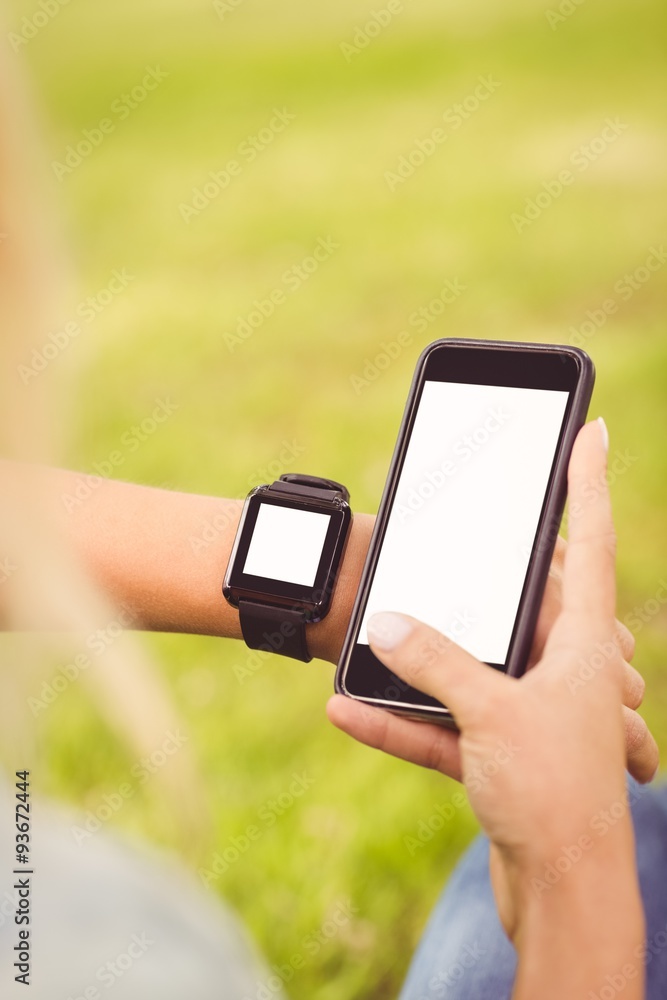 Over shoulder view of woman using smartphone and smartwatch