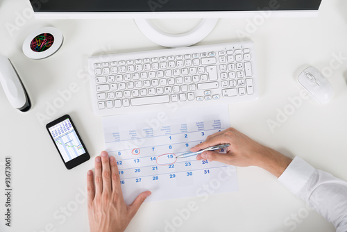 Businessperson Marking Important Date On Calendar