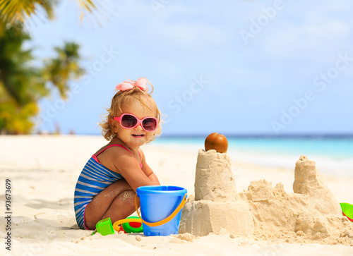 cute little girl playing with sand on beach