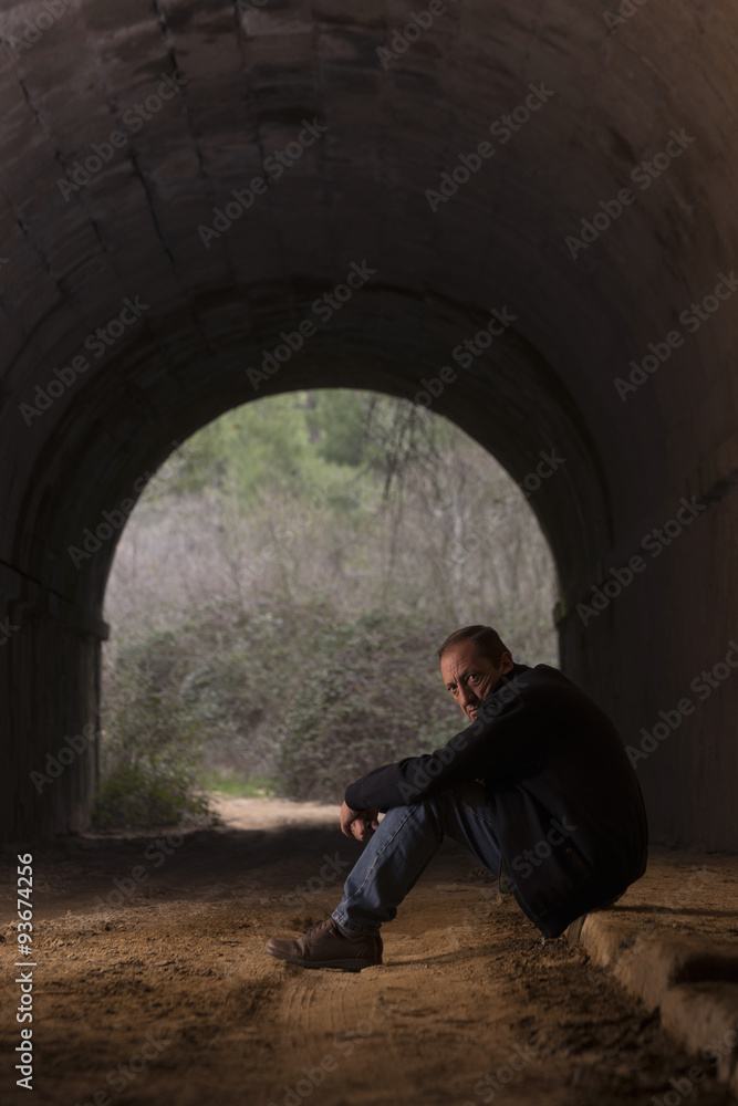 Solitary man sitting in an abandoned tunnel