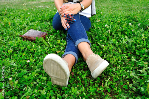  girl in jeans in casual flats resting on green grass with brigh