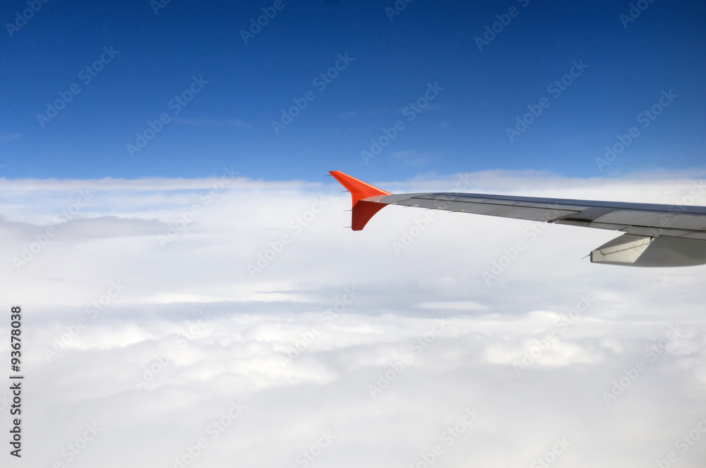 Fototapeta premium The wing of the Airbus above the clouds in the sky, view from above the clouds, flying over clouds in a plane, the boundless space, the atmosphere and meteorology, travel on a passenger plane