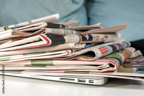 Stack of newspapers, placed on a laptop