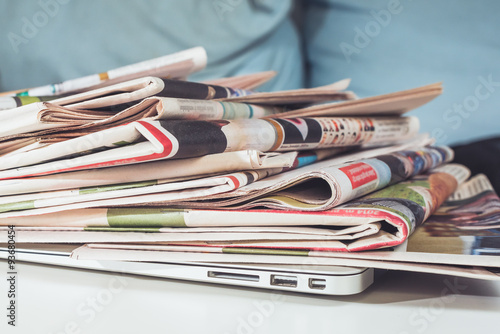 Stack of newspapers, placed on a laptop