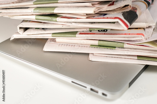 Stack of newspapers, placed on a laptop