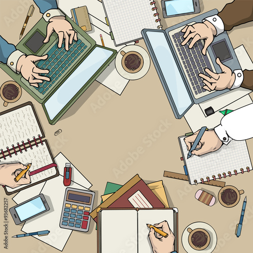 Office desk top view filled with various items, laptop, notebooks, coffee cup, many hands working around the able, office meeting