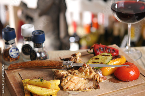 Chicken barbecue with fried potato and red wine on wood table