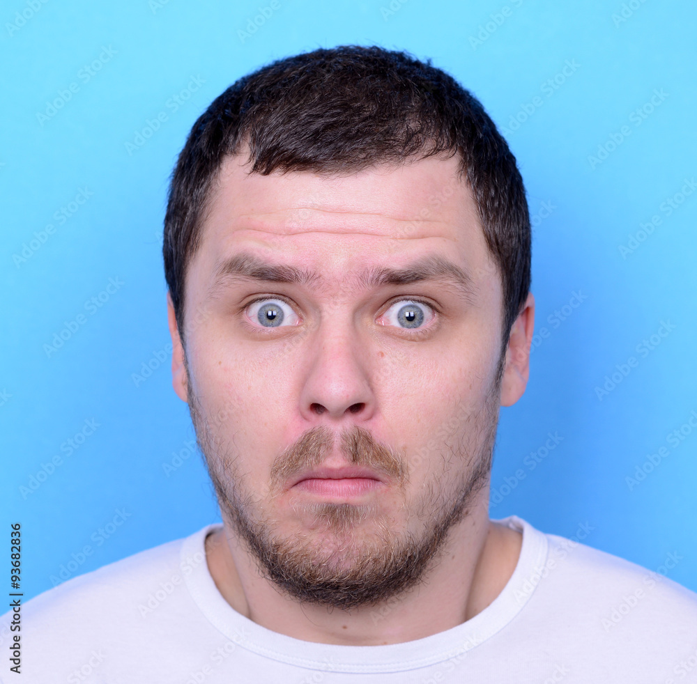 Fototapeta premium Portrait of man with dusgusted gesture against blue background