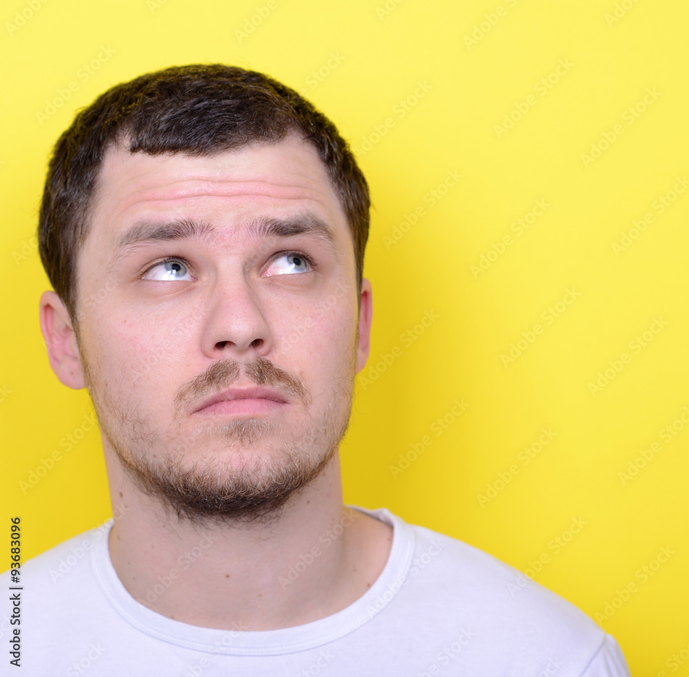 Portrait of happy young man looking up against yellow background Portrait of happy young man looking up against yellow background