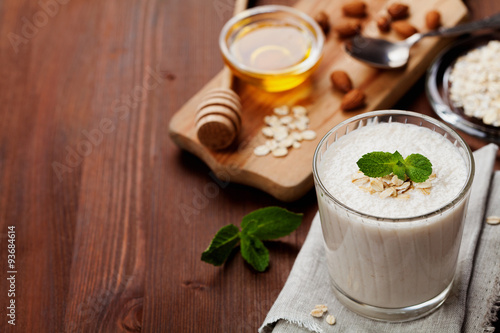 Healthy breakfast of banana smoothie or milkshake with oats and honey decorated mint leaves on rustic surface