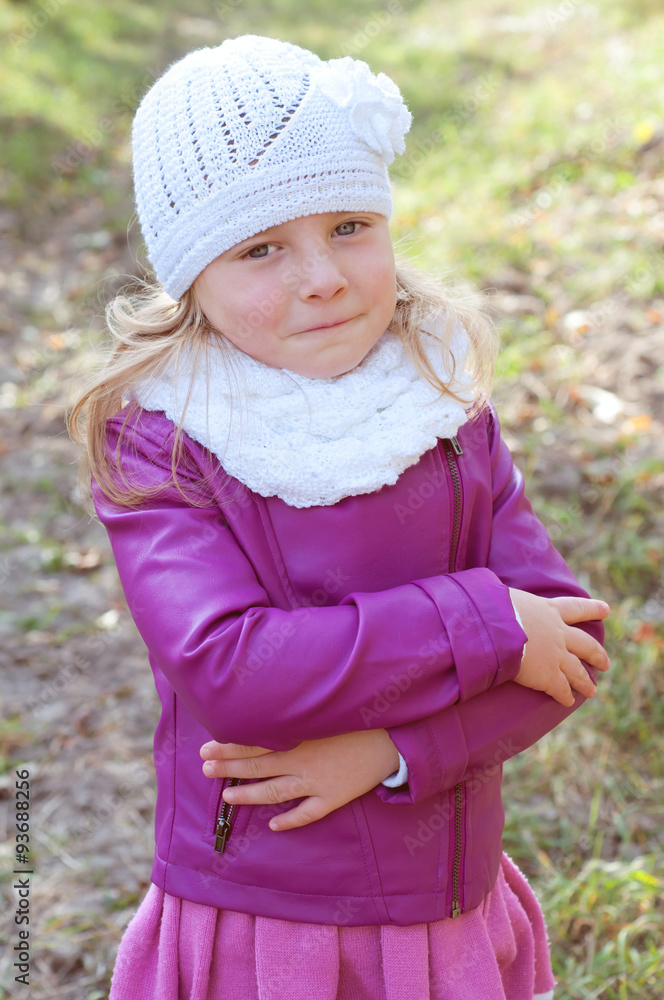 Cute little blond girl in a white knitted hat and scarf. Fall la Cute little blond girl in a white knitted hat and scarf. Fall la