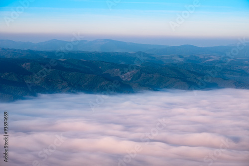 Autumn landscape view of mountain hills above misty clouds at su © Martin M303