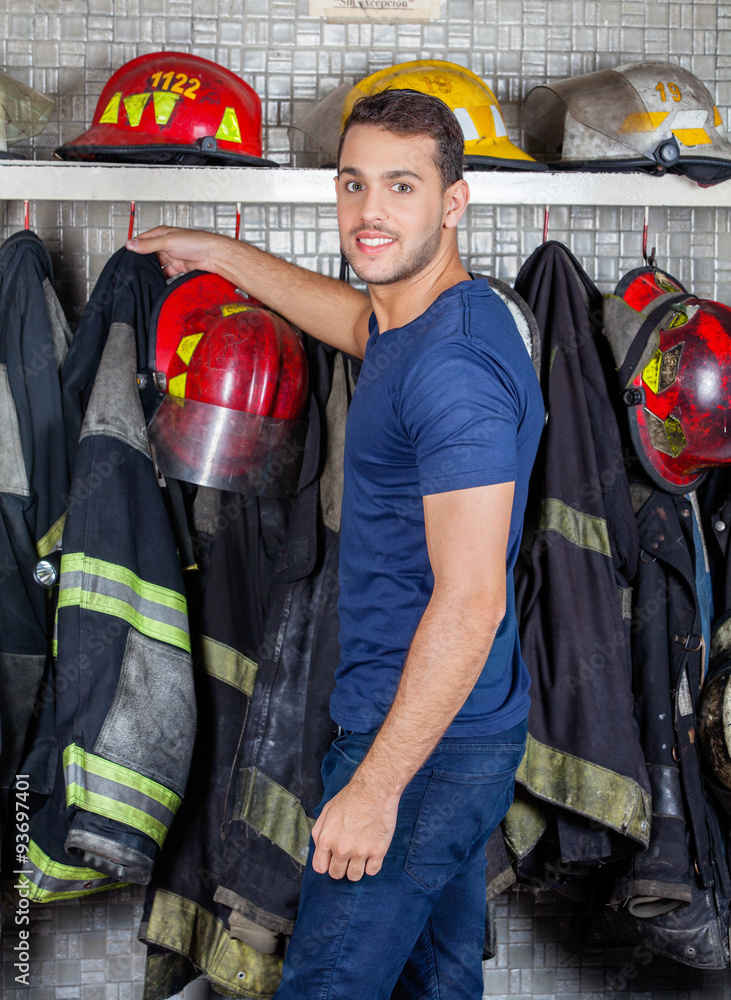 Naklejka premium Fireman Removing Uniform Hanging At Fire Station