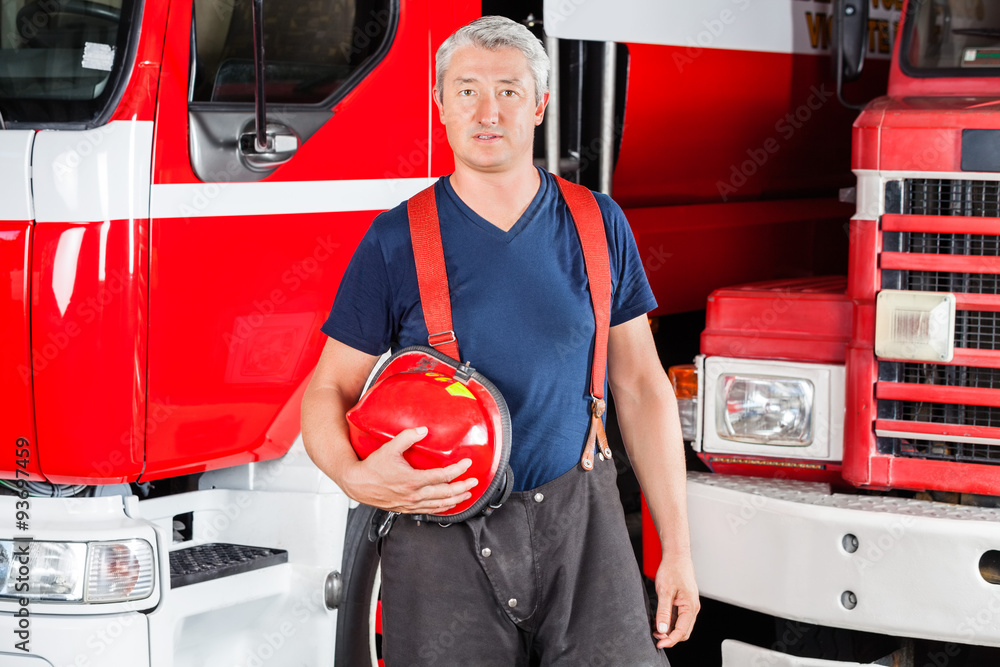Obraz premium Confident Fireman Holding Red Helmet