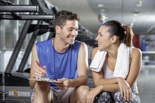  male trainer sitting in gym with client