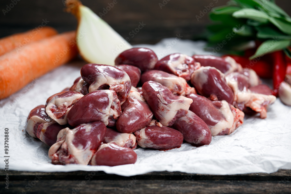 Raw Duck hearts on crumpled paper, decorated with vegetables. on old wooden table. Raw Duck hearts on crumpled paper, decorated with vegetables. on old wooden table.