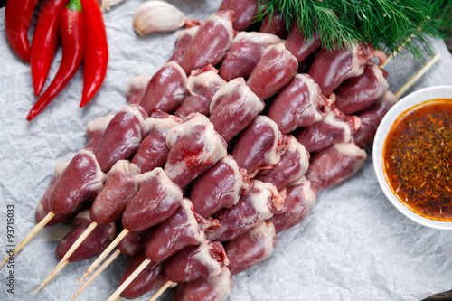Ready to cook Duck Heart stringed on skewers BBQ , chili pepper. decorated with greens and vegetables. background.