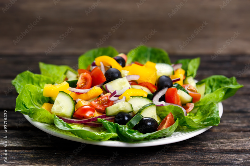 Fresh Vegetable  Salad mix, black olives, cherry tomatoes, yellow pepper, red onion, cucumber. On wooden table