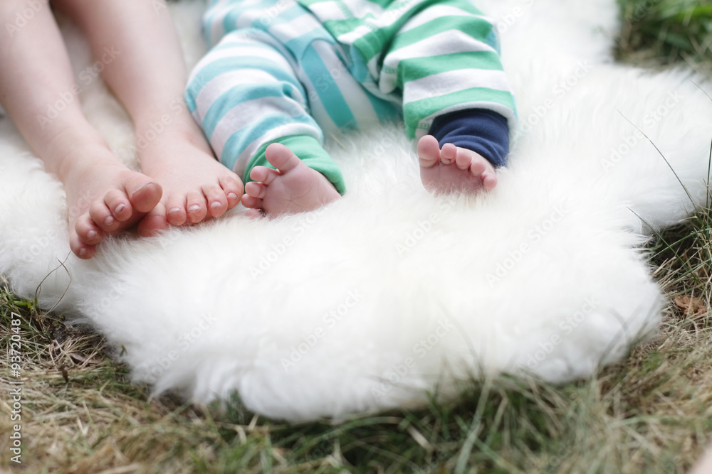 two pair of children's feet lays on white sheep fur two pair of children's feet lays on white sheep fur