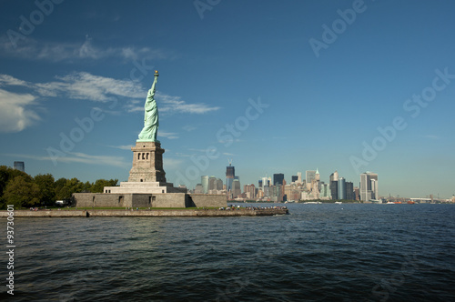 Statue of Liberty on Liberty Island in front of the Manhattan Skyline on a summer day with blue sky, New York City, USA © AR Pictures