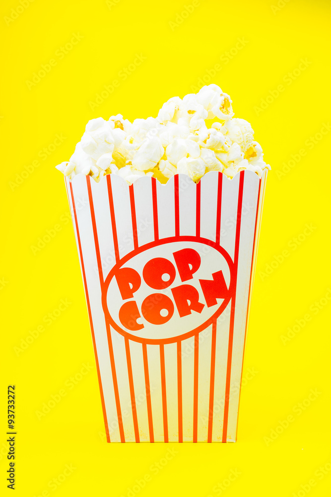 Classic box cinema popcorn on yellow background..