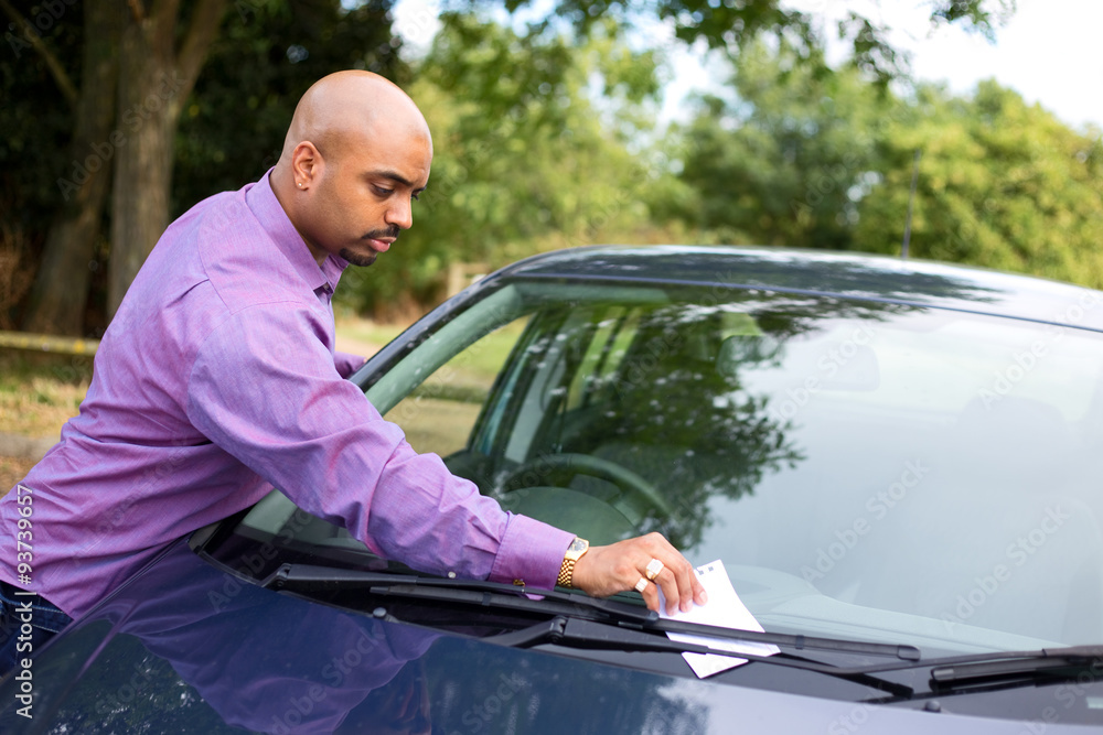 young man leaving a message on a car windscreen