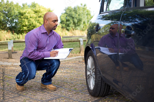 man inspecting the side of a car