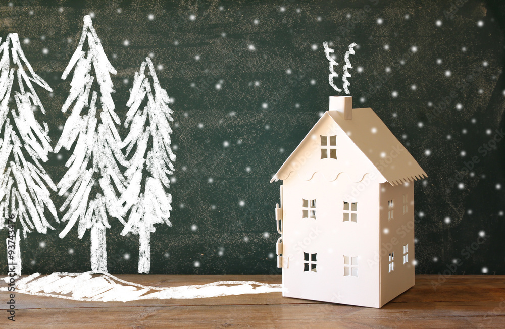 Naklejka premium photo of toy house in front of chalkboard with winter concept drawings 