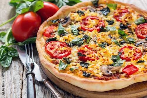 Pizza with tomatoes and cheese close up.