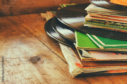 records stack with record on top over wooden table. vintage filtered
 photo