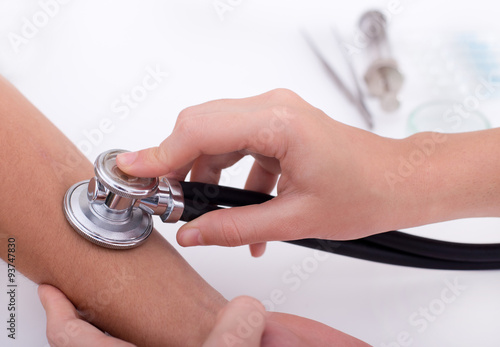Doctor measuring pulse with stethoscope