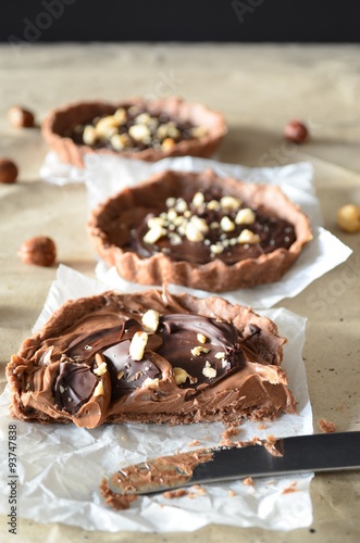 Chocolate tarts decorated with cream and hazelnut 