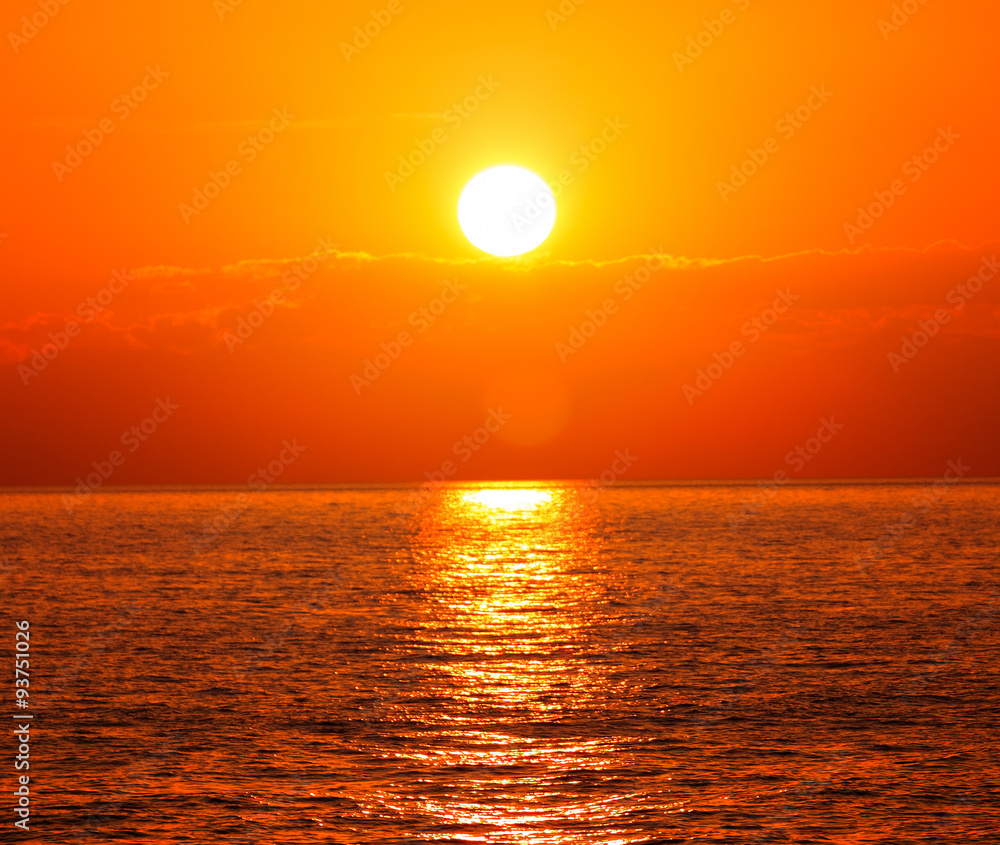 Sunset with orange sun and glittering water