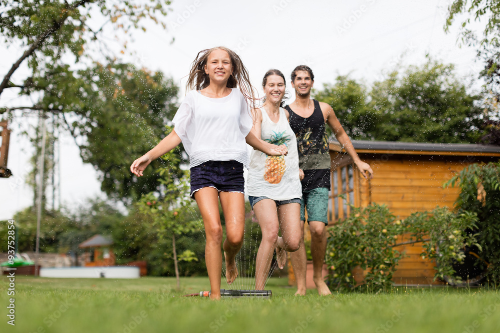 Fototapeta premium Familie läuft über einen Wassersprenger