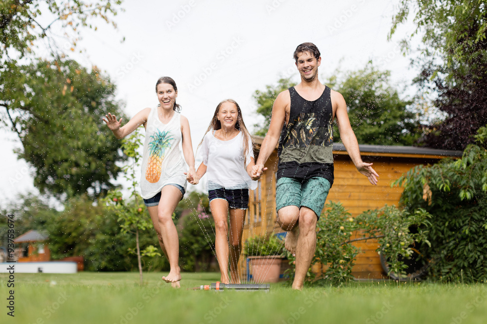 Fototapeta premium Familie läuft über einen Wassersprenger