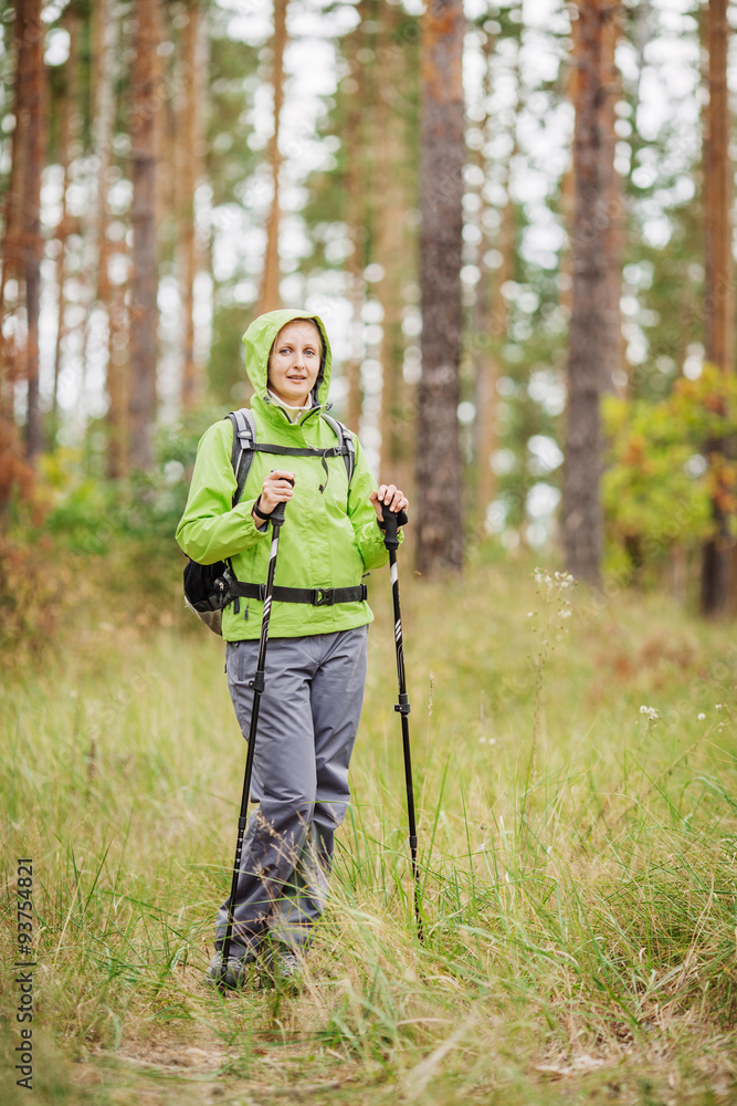woman with hiking equipment walking in forest
