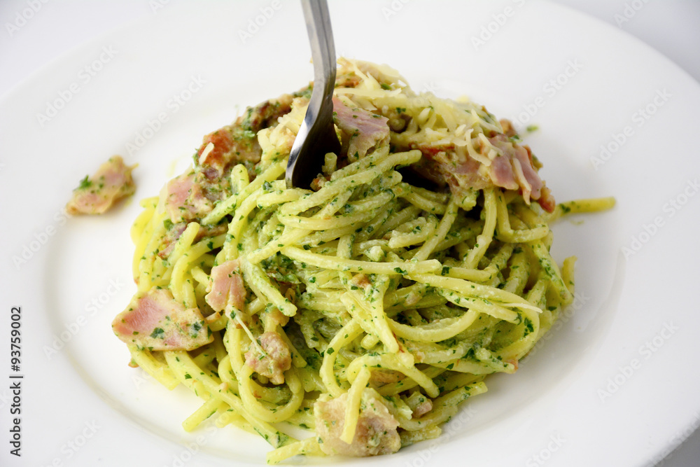 Spaghetti with pesto and bacon on white plate, studio isolated