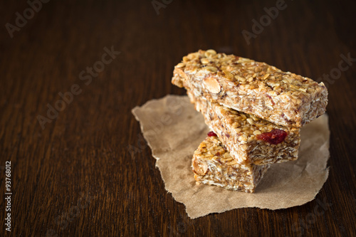 Granola bar or energy bar with oats, dates and nuts on brown wooden background
