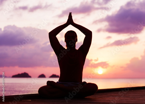 man doing yoga at sunset