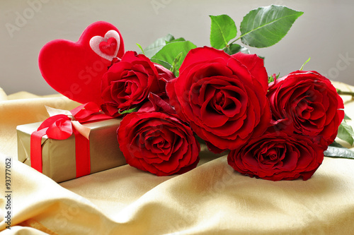 Bouquet  of red roses  with hearts   on golden tablecloth 