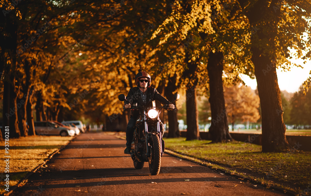 Naklejka premium Man riding a cafe-racer motorcycle outdoors