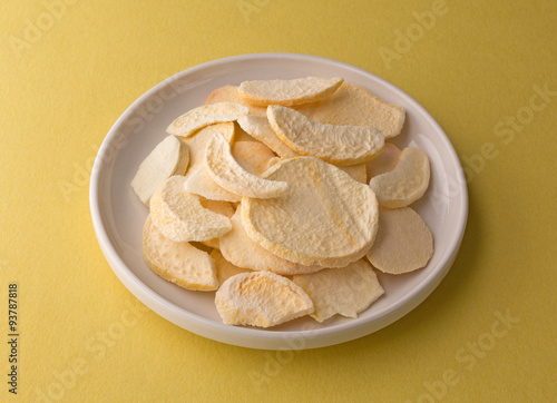 Plate of dried peach slices on a yellow table