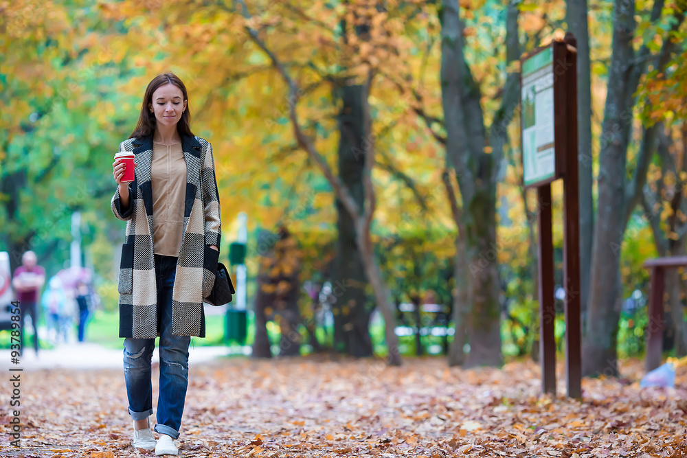 Happy beautiful woman drinking coffee in autumn park under fall Happy beautiful woman drinking coffee in autumn park under fall