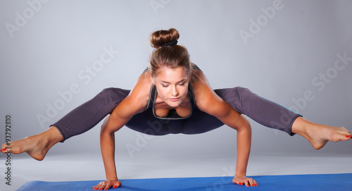 Young woman doing yoga exercise on gray background