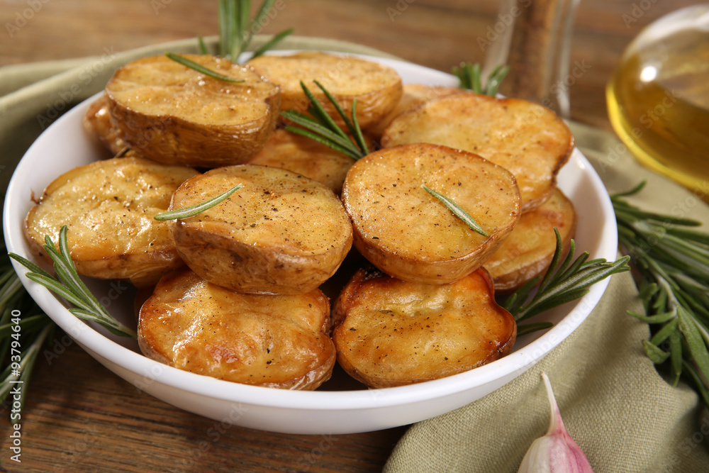 Delicious baked potato with rosemary in bowl on table close up Delicious baked potato with rosemary in bowl on table close up