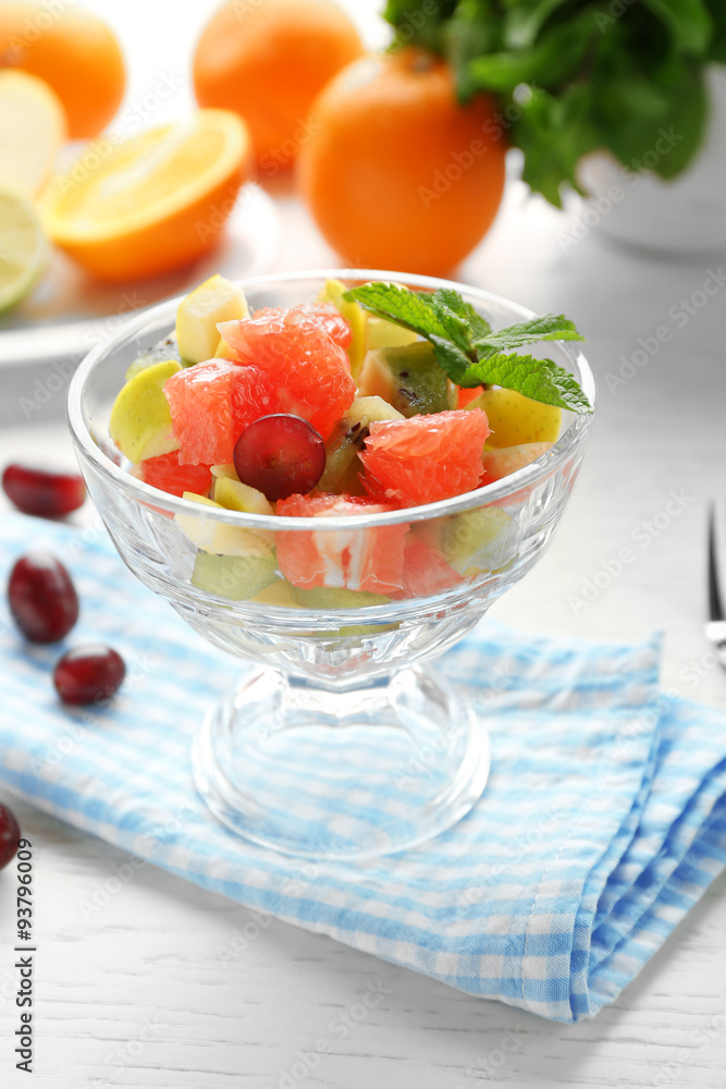 Fruit salad in glass bowl, on light wooden background Fruit salad in glass bowl, on light wooden background