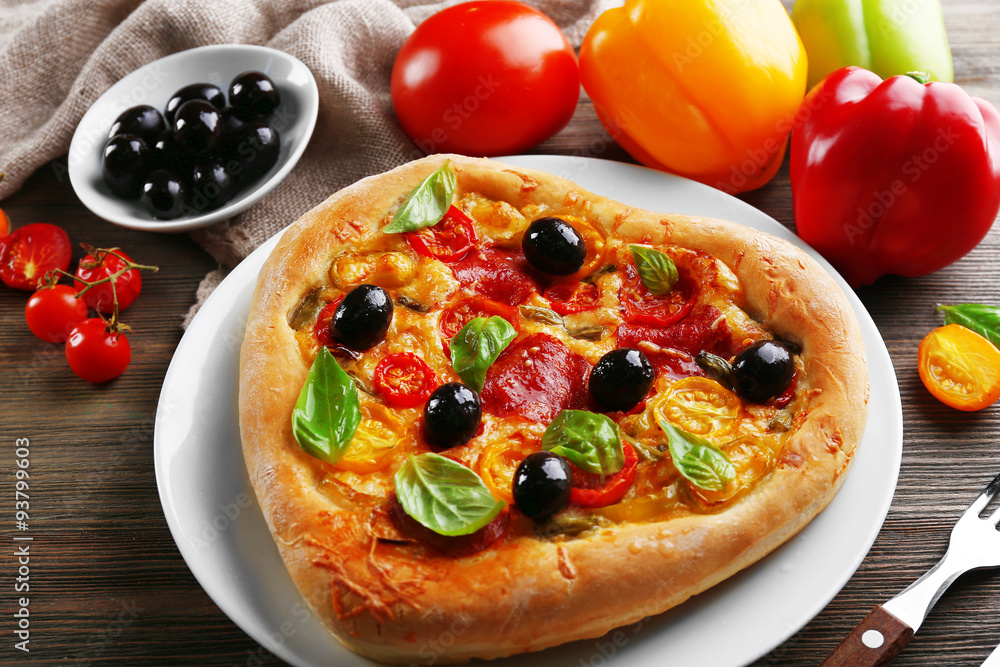 Heart shaped pizza served on plate on wooden background Heart shaped pizza served on plate on wooden background