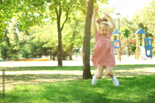 Little happy girl playing in park near the playground